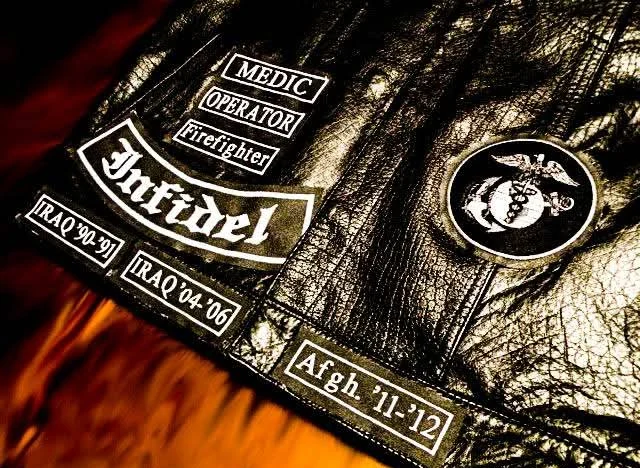Embroidered trade tabs and deployment tabs on a black leather motorcycle vest front, made by Independence Embroidery.