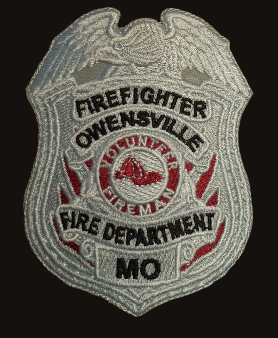 An embroidered shield badge patch for the Owensville, Missouri Fire Department, stitched in grey, white and red.