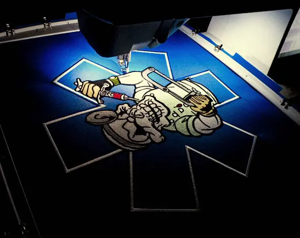 An embroidered patch under the needle of a commercial machine mid-run, at Independence Embroidery in Owensville, Missouri.