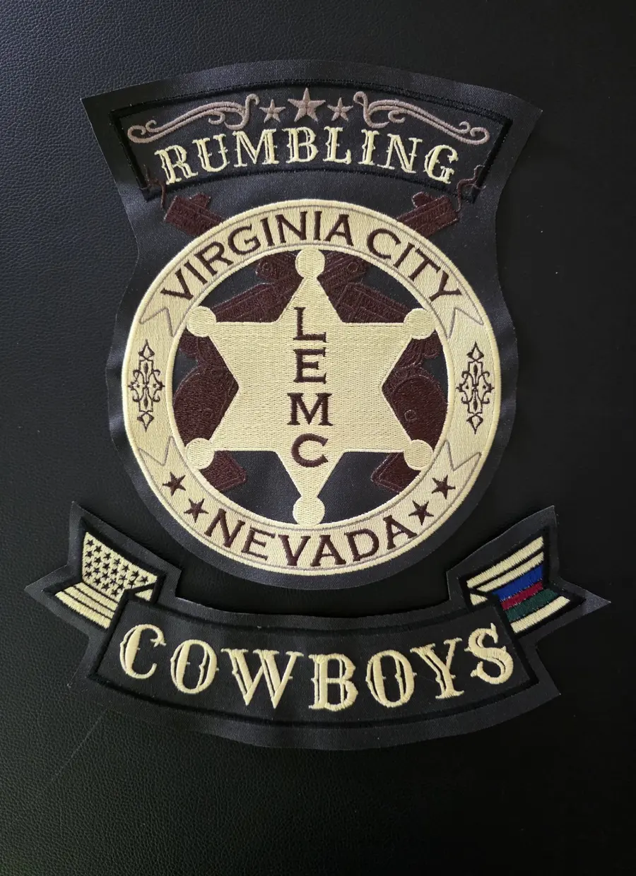 Three finished embroidered patches laid out on black leather after stitching, at Independence Embroidery in Owensville, Missouri.