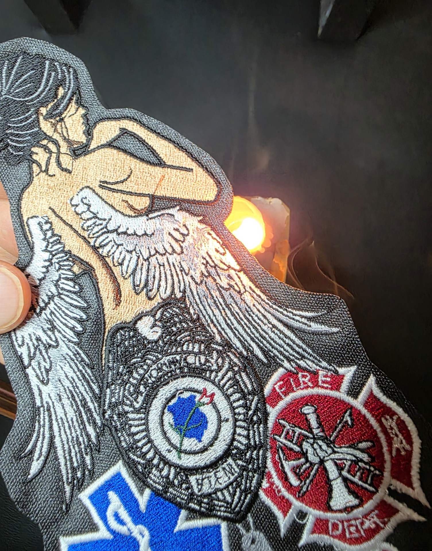 A close view of an embroidered patch edge being sealed over an open flame.