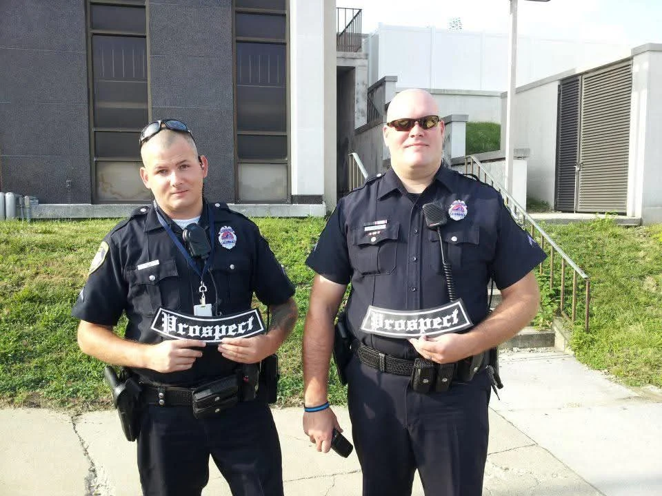 Two uniformed police officers holding embroidered Prospect patches, made by Independence Embroidery in Owensville, Missouri.