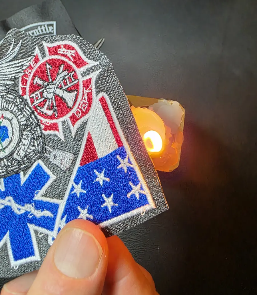 The edge of a finished embroidered patch held to an open flame as a final sealing step.